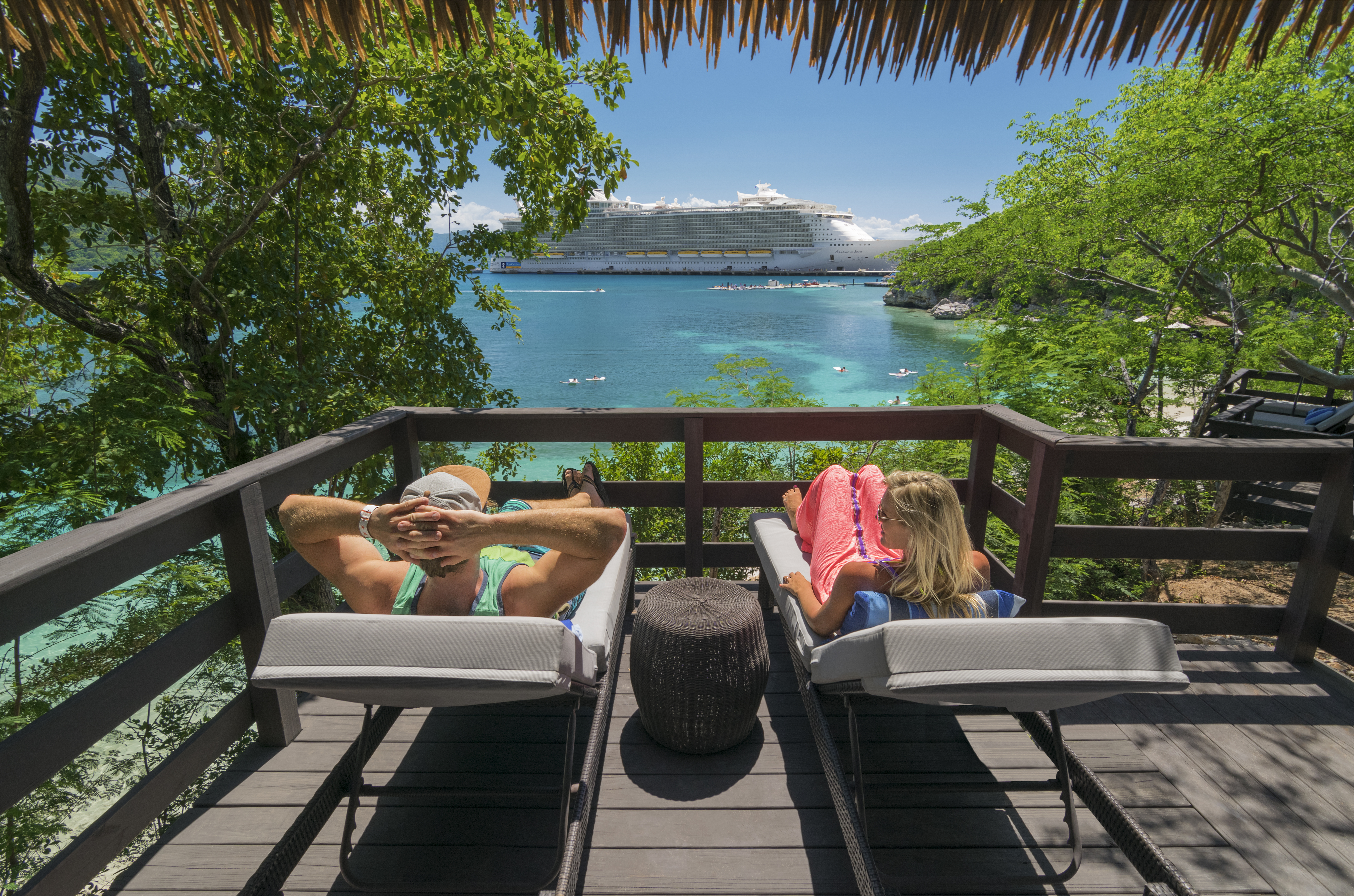 Pariskunta ottamassa aurinkoa ja taustalla Royal Caribbeanin Allure of the Seas. 